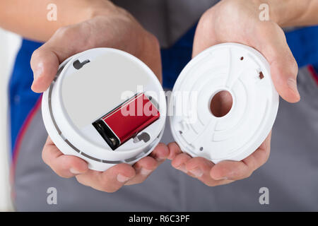 Person's Hand Inserting Battery In Smoke Detector Stock Photo