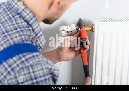 Male Plumber Fixing Thermostat Using Wrench Stock Photo