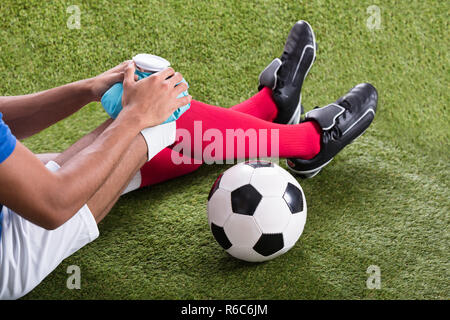 Injured Soccer Player Applying Ice Pack On Knee Stock Photo
