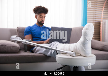 Man With Broken Leg Using Laptop Stock Photo