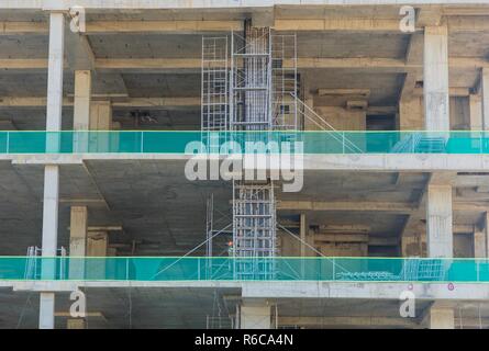 A concrete construction on a building site with concrete pillars and scaffolding with green safety netting in central Vietnam. Stock Photo