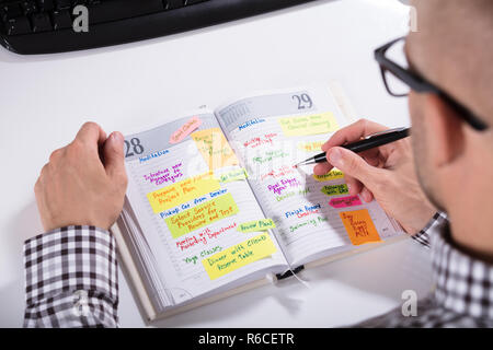 Man Writing Important Notes In Diary Stock Photo