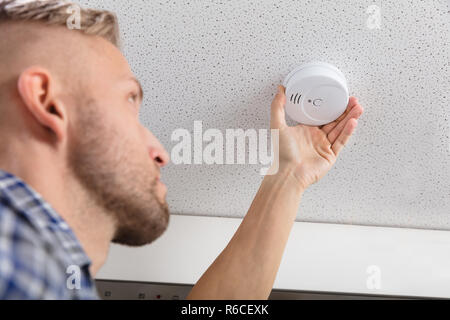 Person's Hand Installing Smoke Detector On Ceiling Stock Photo