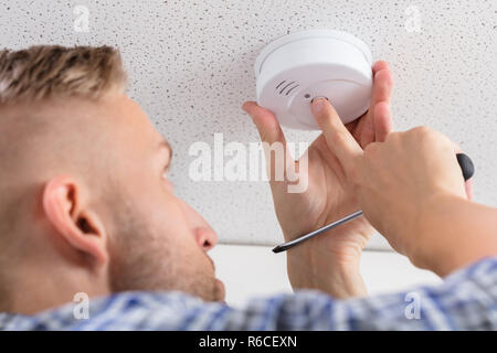 Person's Hand Installing Smoke Detector On Ceiling Stock Photo