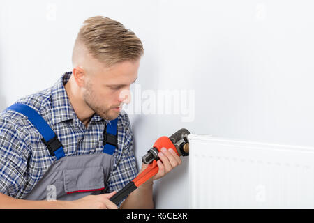 Male Plumber Fixing Thermostat Using Wrench Stock Photo