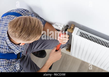 Male Plumber Fixing Thermostat Using Wrench Stock Photo