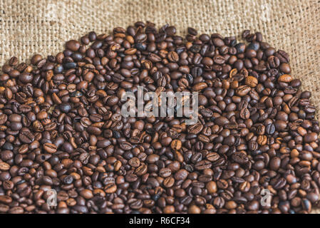 Heap of Roasted Coffee Beans on Burlap Background Stock Photo