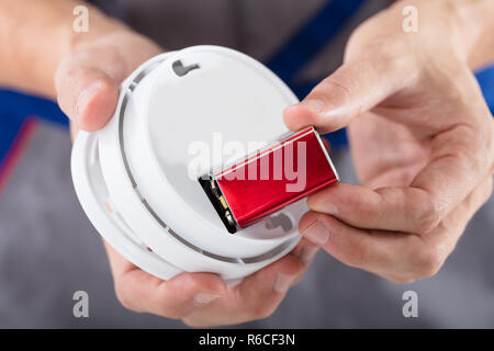 Person's Hand Inserting Battery In Smoke Detector Stock Photo