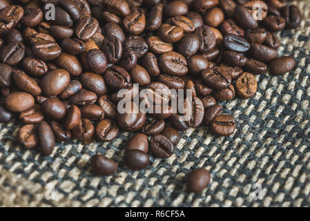Heap of Roasted Coffee Beans on Burlap Background Stock Photo