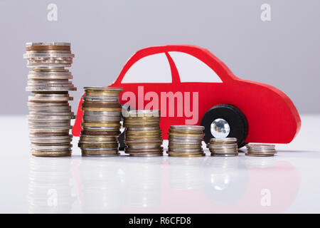 Red Car Over Stacked Coins Stock Photo