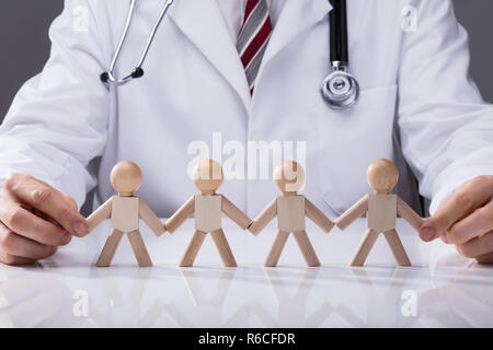 Doctor's Hand Holding Hand Of Wooden Figures Stock Photo