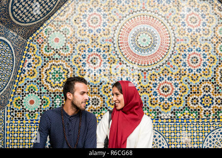 Young Muslim couple in relationship talking and smiling in front of arabesque oriental decoration Stock Photo