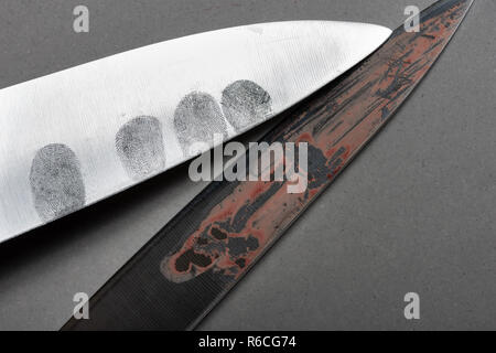 Dusted finger prints showing up as forensic eveidence on a sharp steel sharp large bladed knife with human blood stains Stock Photo