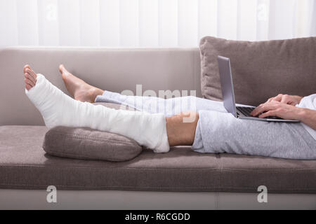 Man With Broken Leg Using Laptop Stock Photo