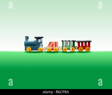 Colourful wooden toy train against a green background Stock Photo