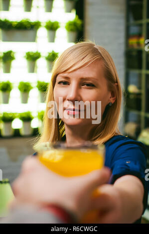 woman housewife setting table. young blonde in dress and apron, served in dining table, puts dishes, doing work in kitchen. pours orange juice yellow drinking Stock Photo