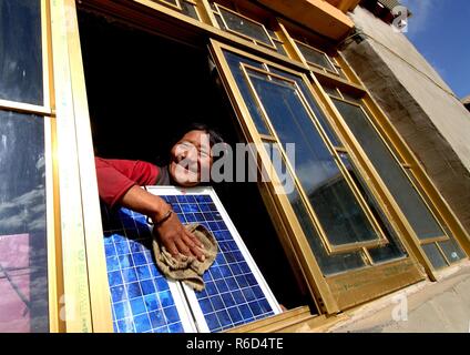(181205) -- BEIJING, Dec. 5, 2018 (Xinhua) -- A woman cleans a solar panel at her new house thanks to the 'Guangming' Project, which was drived by the Chinese government in 1997 to solve the power supply of no-electricity regions by developing new energy electricity generation, in southwest China's Tibet Autonomous Region, Oct. 12, 2006.    China has been delivering on its commitment to the international community on climate change by continuously shifting to a more green economy over the past years.     New energy-rich regions like Inner Mongolia and Ningxia are sending more electricity gener Stock Photo