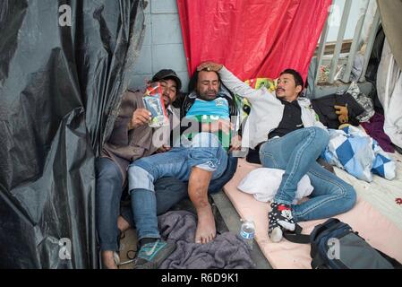 Tijuana, Mexico. 04th Dec, 2018. Migrants rest in front of the Benito Juarez sports complex, which was closed due to flooding. Currently more than 6000 migrants from Central America are waiting in the border town of Mexican Tijuana to apply for asylum in the USA. As only a limited number of cases are processed at the San Ysidro border crossing, there are months of waiting time. Credit: Bruno Gallardo/dpa/Alamy Live News Stock Photo