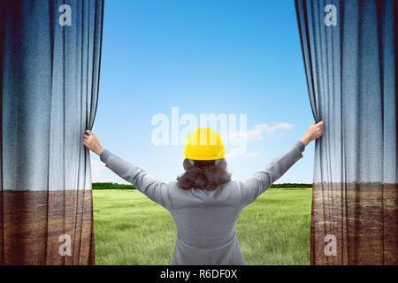 Attractive architect woman opening curtains and looking green landscape Stock Photo