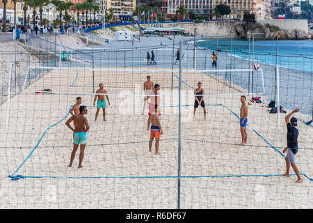 Nice, France - October 1, 2018: Group of men playing volleyball inside sand court at Mediterranean beach of Nice, France. Stock Photo