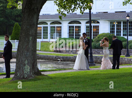 Plainville, CT USA. June 2013. Seniors at prom night having fun and taking pictures while young man by the tree anxiously waiting for his date. Stock Photo