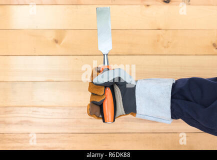 Hand in glove holding chisel Stock Photo