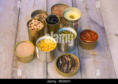 Different open canned food on old wooden background. Stock Photo
