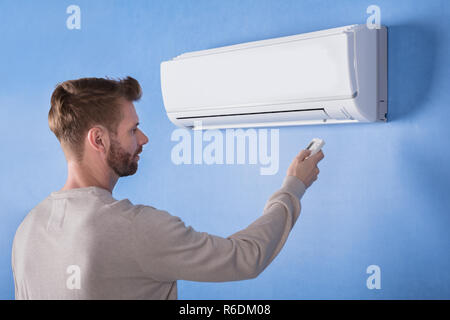 Rear View Of A Young Man Operating Air Conditioner Stock Photo
