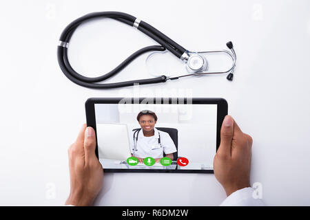 Doctor Video Conferencing With Male Colleague On Digital Tablet Stock Photo