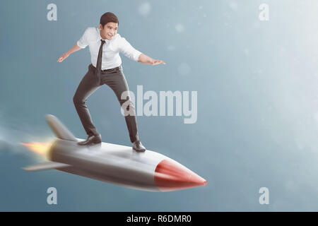 Portrait of asian businessman standing on flying rocket Stock Photo