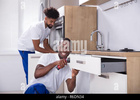 Repairmen Fixing The Wooden Cabinet In The Kitchen Stock Photo