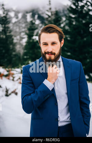 groom in a blue suit in the mountains Carpathians Stock Photo