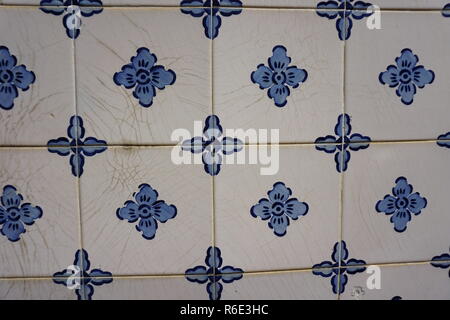 Lisbon / Portugal - May 2017: Portuguese traditional painted tin-glazed ceramic tiles Azulejos with plain blue flowers in ornament and cracks in white Stock Photo