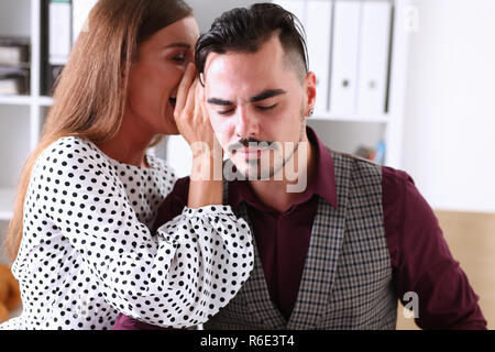 Woman gossip whispers in the ear of news to a man Stock Photo