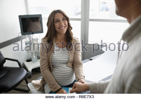 https://l450v.alamy.com/450v/r6e7x3/smiling-hopeful-pregnant-woman-holding-hands-with-husband-in-clinic-examination-room-r6e7x3.jpg