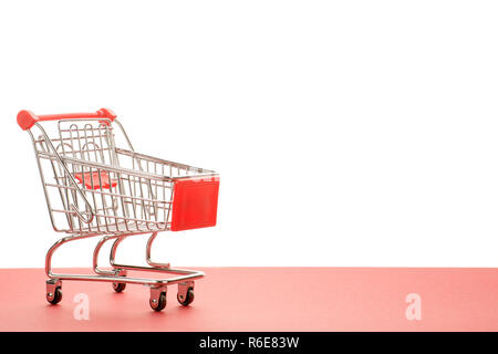 Small empty shopping cart with red handle. On red and white background with copy space Stock Photo