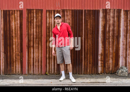 Young bearded man standing while posing and wearing cap against  Stock Photo