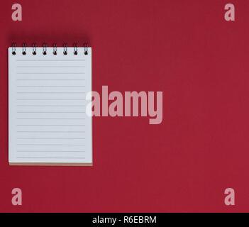 small notebook with empty white sheets in line, red background, empty space Stock Photo