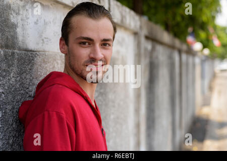 Young happy bearded man smiling while wearing red hoodie and lea Stock Photo