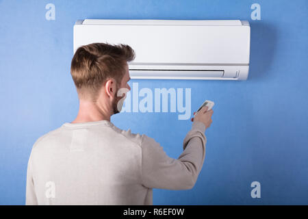 Rear View Of A Young Man Operating Air Conditioner Stock Photo