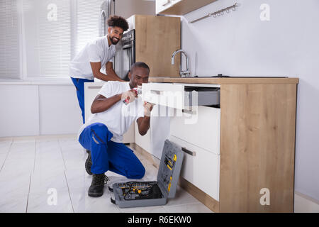 Repairmen Fixing The Wooden Cabinet In The Kitchen Stock Photo