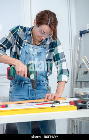 pretty young smiling woman using cordless drill Stock Photo