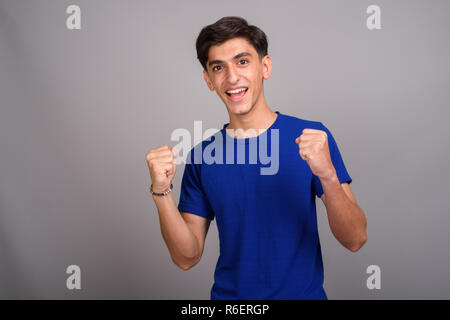Young happy Persian teenage boy smiling with arms raised Stock Photo