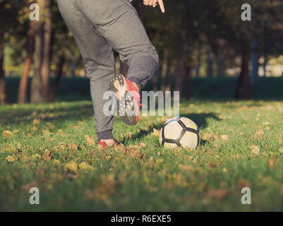 Soccer Player Kicking Football in the Park on a Sunny Autumn Day Stock Photo