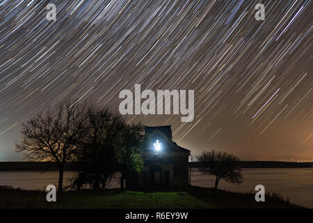 Star trails over an abandoned church in Romania Stock Photo