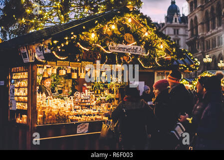 Vienna, Austria - December 24, 2017. People buying souvenirs and gifts at traditional winter Christmas market. Illuminated Xmas fair kiosk with candle Stock Photo