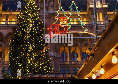 Vienna, Austria - December 24, 2017. Illuminated decorative garland with Santa Claus, Christmas tree and lights at traditional Viennese Christmas mark Stock Photo