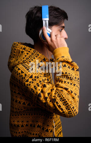 Profile view of young handsome Persian teenage boy with headphones Stock Photo