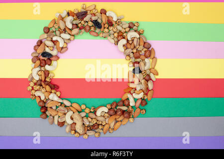 Pattern of nuts in circle form. Various nuts on colorful paper background.  Roasted chickpea, almond, hazelnut, fig, peanut, pistachio, mulberry, grap Stock Photo