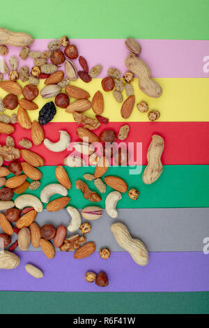 Assorted nuts scattered on a colorful paper background top view Stock Photo